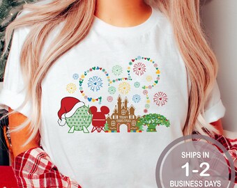 May include: White t-shirt with a Christmas-themed design featuring Mickey Mouse, a castle, and a Christmas tree. The design includes a string of lights and fireworks. The text "Merry Christmas" is included in the design.