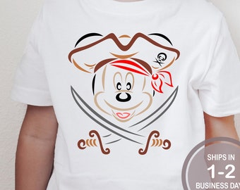 May include: White t-shirt with a brown and red pirate Mickey Mouse design. The design features Mickey Mouse wearing a pirate hat and bandana with crossed swords behind him.