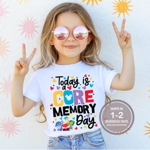 May include: White t-shirt with a colorful graphic that says "Today is a CORE MEMORY Day" with the Disney characters from the movie Inside Out. The graphic also includes Mickey Mouse ears.