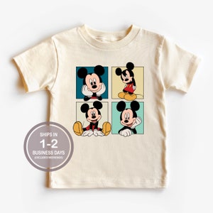 Pu&ograve; includere: Una maglietta color crema con una grafica di quattro immagini di Topolino disposte in una griglia. Ogni immagine ha un colore di sfondo diverso e Topolino &egrave; in una posa diversa. La maglietta ha maniche corte e un collo rotondo.
