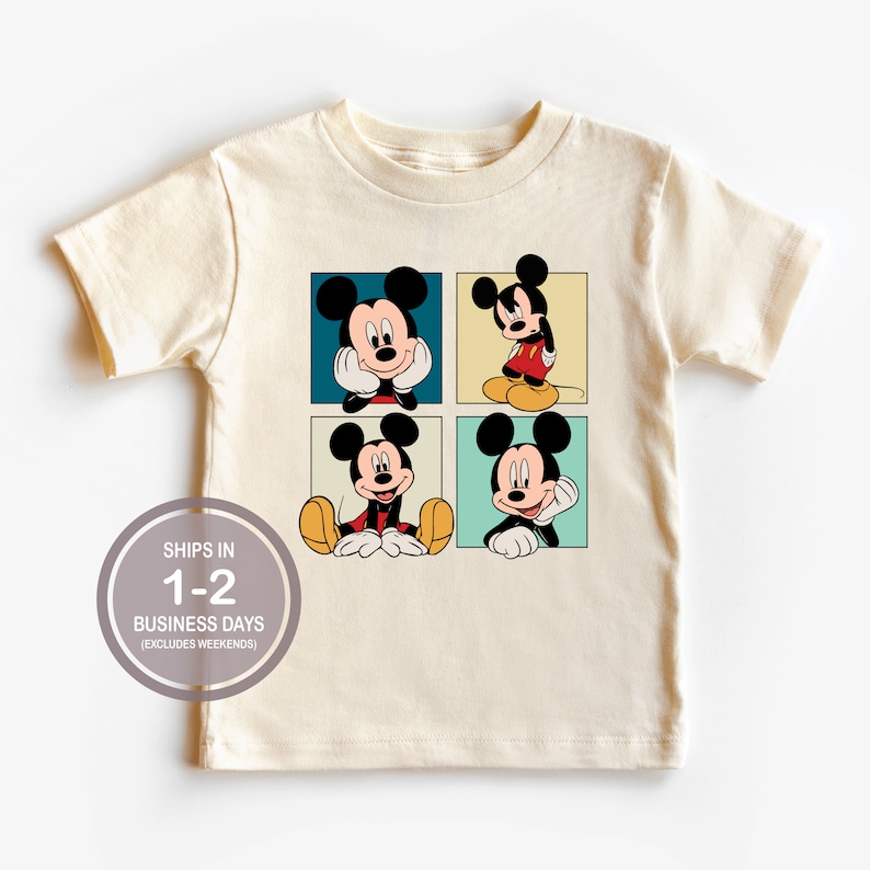 Pu&ograve; includere: Una maglietta color crema con una grafica di quattro immagini di Topolino disposte in una griglia. Ogni immagine ha un colore di sfondo diverso e Topolino &egrave; in una posa diversa. La maglietta ha maniche corte e un collo rotondo.