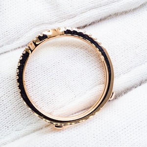 Puede incluir: Un anillo de banda de oro rosa con una fila de peque&ntilde;os diamantes alrededor de la banda. El anillo tiene cuatro peque&ntilde;as garras en la parte inferior.