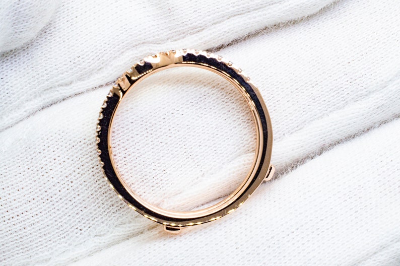 Puede incluir: Un anillo de banda de oro rosa con una fila de peque&ntilde;os diamantes alrededor de la banda. El anillo tiene cuatro peque&ntilde;as garras en la parte inferior.