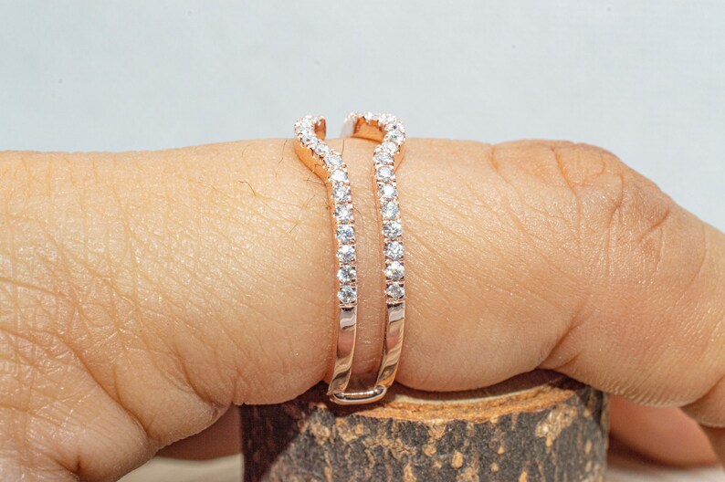 Puede incluir: Un engastador de anillo de oro rosa con un dise&ntilde;o delicado y curvado. El engastador est&aacute; engastado con peque&ntilde;os diamantes transparentes.