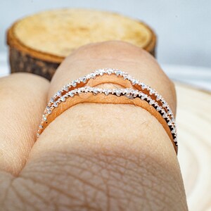 Puede incluir: Dos delicados anillos de oro rosa con una fila de peque&ntilde;as piedras transparentes engastadas alrededor de la banda.