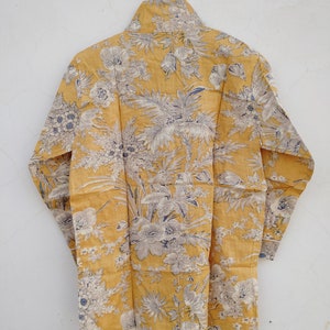 May include: A yellow long-sleeved shirt with a floral print. The shirt has a high neck and a relaxed fit.