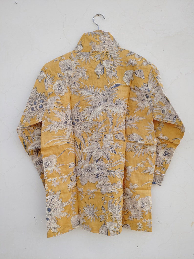 May include: A yellow long-sleeved shirt with a floral print. The shirt has a high neck and a relaxed fit.
