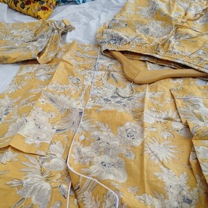 May include: A set of yellow pajamas with a white floral print. The pajamas feature a button-up top and matching pants.