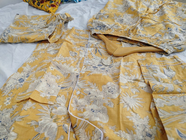 May include: A set of yellow pajamas with a white floral print. The pajamas feature a button-up top and matching pants.