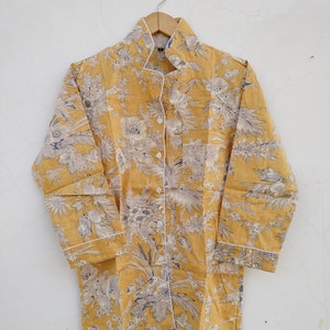 May include: A yellow button-up shirt with a floral print and white trim. The shirt has a collar and long sleeves.
