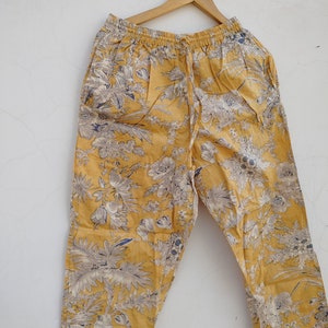May include: Yellow pants with a floral print. The pants have an elastic waistband and a drawstring.