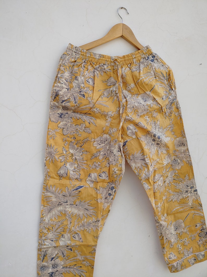 May include: Yellow pants with a floral print. The pants have an elastic waistband and a drawstring.