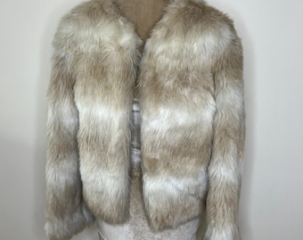 May include: A faux fur jacket with a striped pattern in shades of brown and white. The jacket has a cropped length and long sleeves.