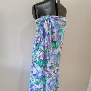 Puede incluir: Una falda de envoltura de estampado floral azul y morado. La falda está atada a la cintura y tiene una silueta fluida.