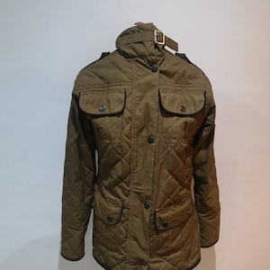 May include: A quilted jacket in a dark olive green color with a black trim. The jacket has a zipper closure, a button placket, and a buckle at the collar.