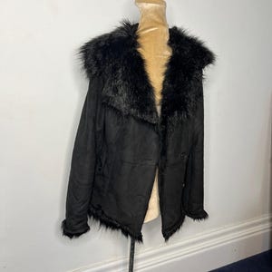 May include: A black faux fur collared jacket with a button closure. The jacket has a suede-like texture and a slightly frayed hem.