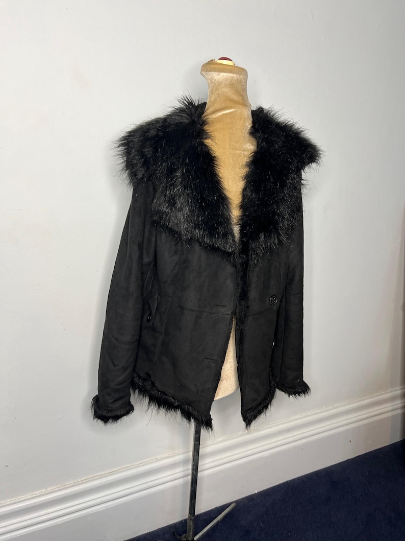 May include: A black faux fur collared jacket with a button closure. The jacket has a suede-like texture and a slightly frayed hem.