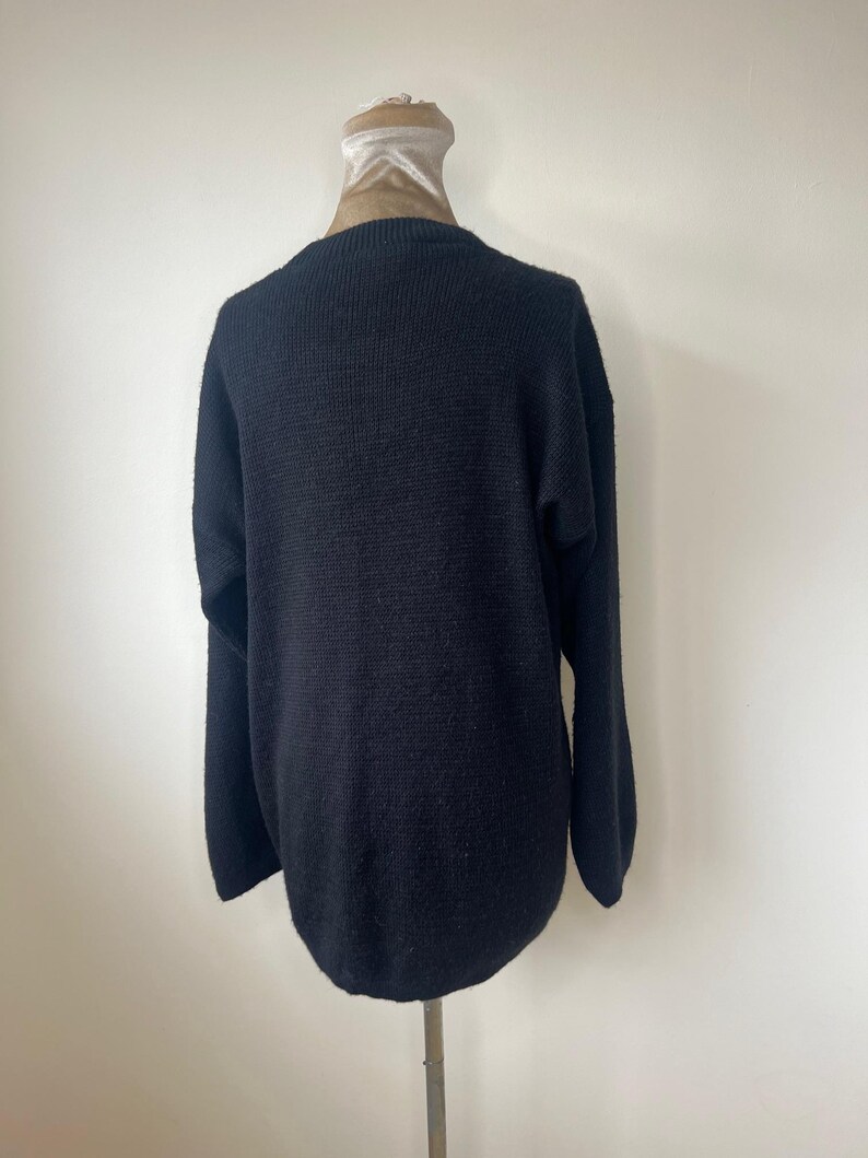 May include: A black knitted sweater with a ribbed texture.