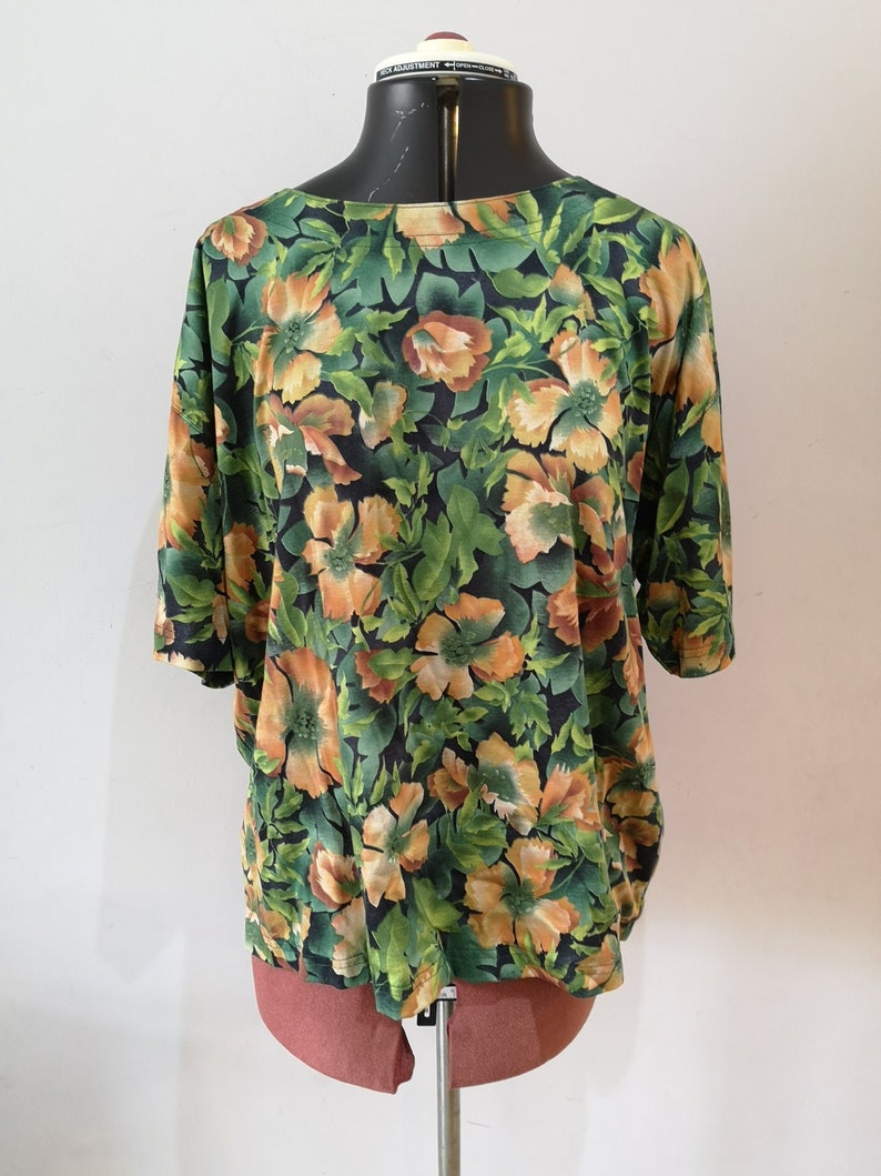 May include: A green and orange floral print blouse with short sleeves.