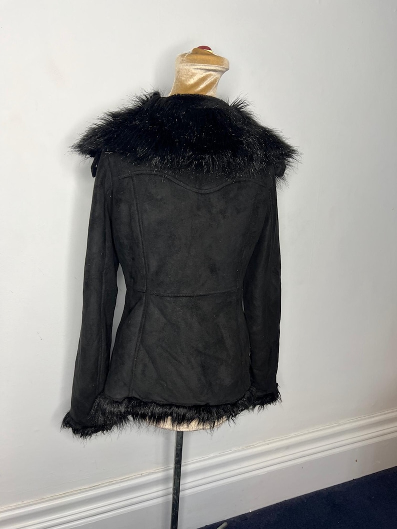 May include: Black faux fur-trimmed suede jacket with a zip-up front and long sleeves.