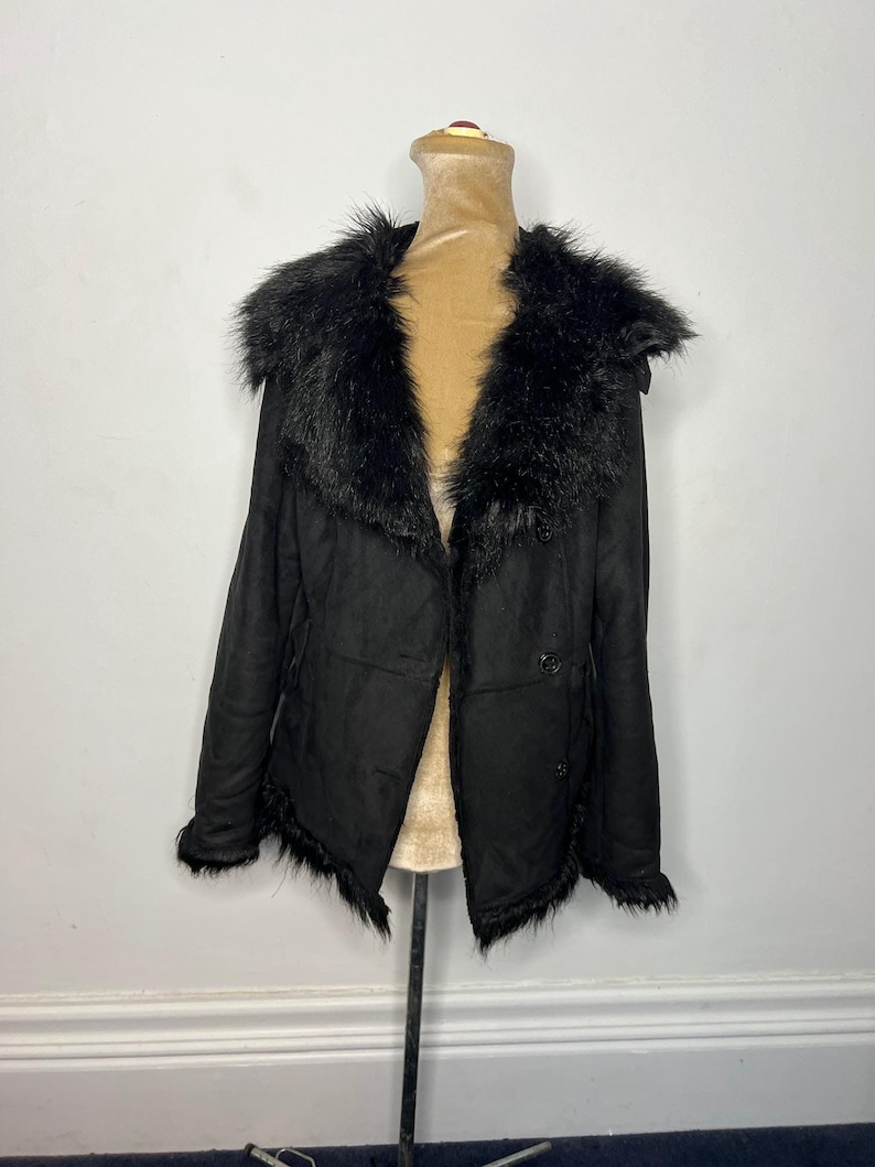 May include: Black faux fur collar jacket with a button closure. The jacket has a frayed hem and a soft, suede-like texture.
