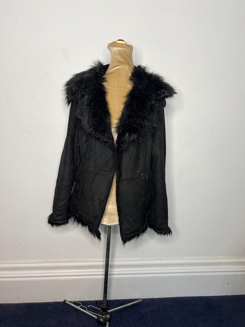 May include: A black faux fur-trimmed suede jacket with a button closure.