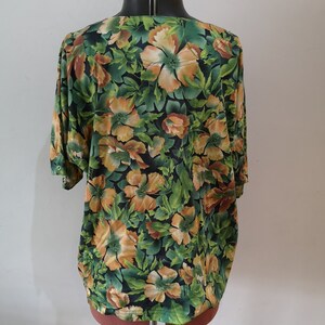 May include: A green, orange, and brown floral print blouse with short sleeves.