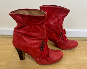 May include: A pair of red leather ankle boots with a lace-up front and a high heel.