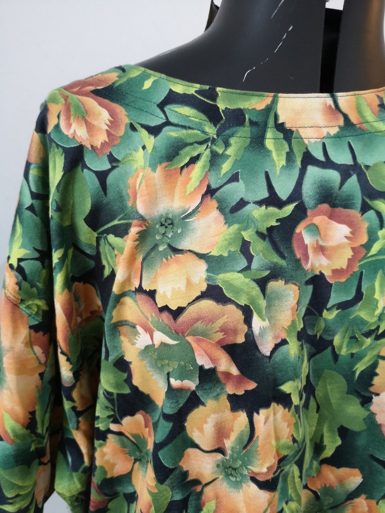 May include: A black and green floral print blouse with orange flowers. The blouse has a scoop neck and short sleeves.