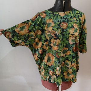 May include: A green and orange floral print blouse with a loose fit and short sleeves.