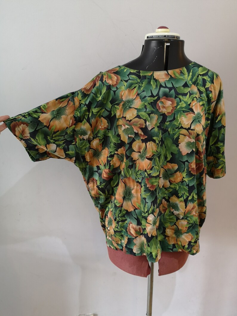 May include: A green and orange floral print blouse with a loose fit and short sleeves.