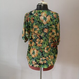 May include: A green and orange floral print blouse with a scoop neck and short sleeves.
