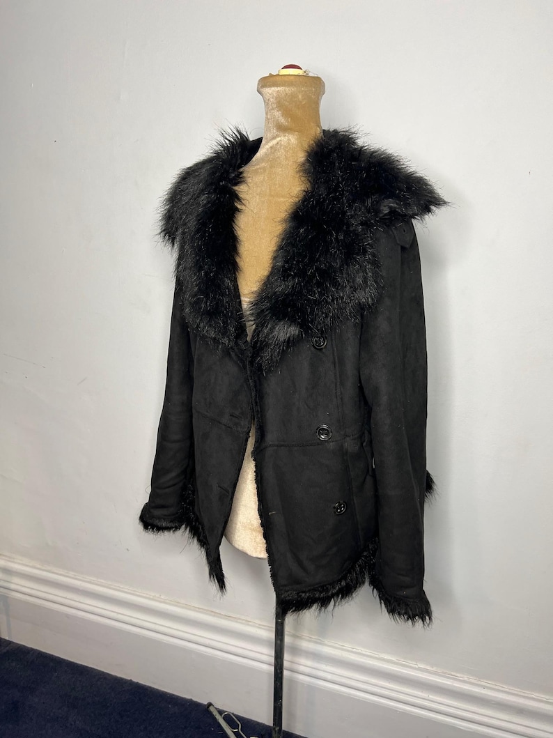 May include: Black faux fur collar jacket with a double breasted closure and a long sleeve design.