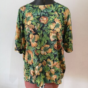 May include: A green and orange floral print blouse with short sleeves.