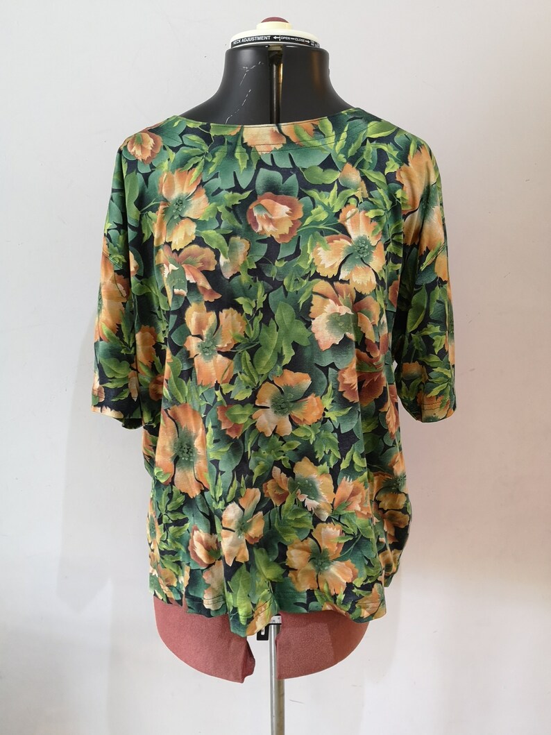 May include: A green and orange floral print blouse with short sleeves.