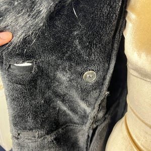 May include: Black faux fur collar jacket with a button closure. The jacket is made of a soft, plush fabric.