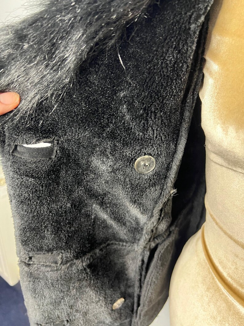 May include: Black faux fur collar jacket with a button closure. The jacket is made of a soft, plush fabric.