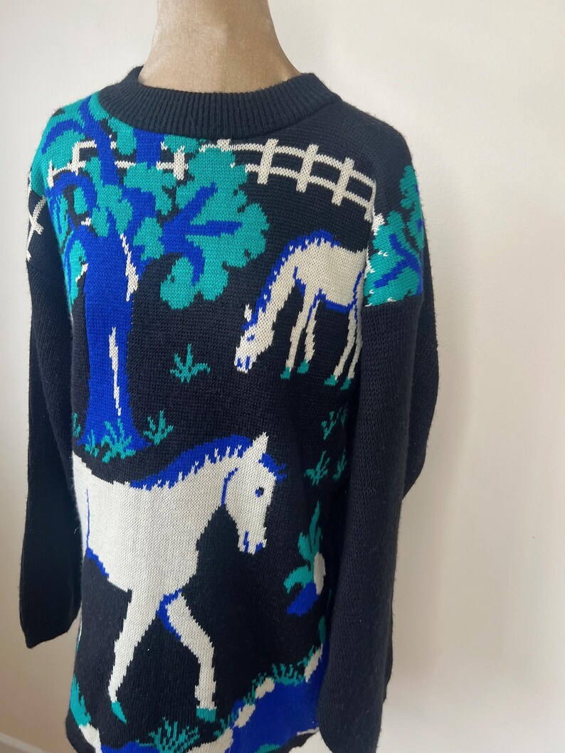 May include: Black sweater with a white horse, blue tree, and green leaves knit into the design.