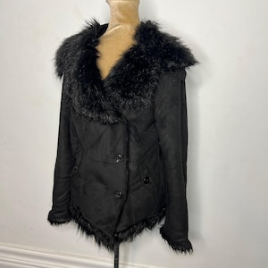 May include: Black faux fur collar jacket with a button closure. The jacket has a slightly fitted silhouette and a faux fur trim around the hem.