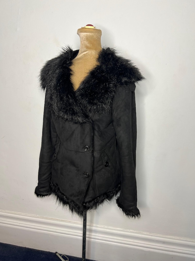 May include: Black faux fur collar jacket with a button closure. The jacket has a slightly fitted silhouette and a faux fur trim around the hem.