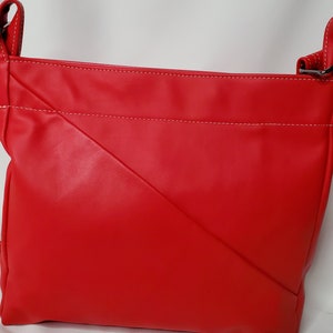 May include: A red leather crossbody bag with white stitching. The bag has a flap closure and a long adjustable strap.
