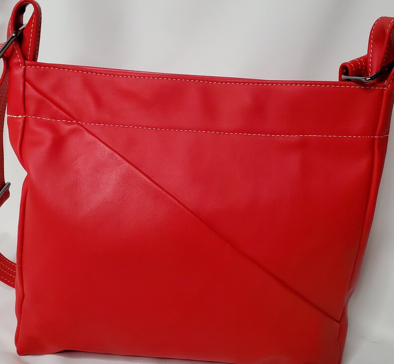 May include: A red leather crossbody bag with white stitching. The bag has a flap closure and a long adjustable strap.