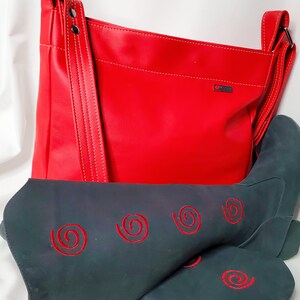 May include: A red leather handbag with a long strap and a black boot with red embroidered swirls. The handbag has a white stitching detail and a small logo.