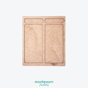 Könnte beinhalten: Ein Holztablett mit zwei rechteckigen Fächern und einem kleinen rechteckigen Fach oben. Das Tablett ist aus hellem Holz gefertigt und trägt im unteren rechten Eck das Logo "montessori factory".