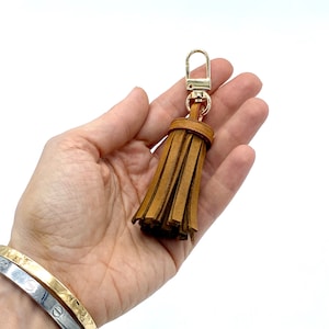 May include: A brown leather tassel keychain with a gold metal clasp.