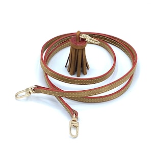 May include: A brown leather strap with red stitching and a brown leather tassel. The strap has gold-toned hardware and is approximately 50 inches long.