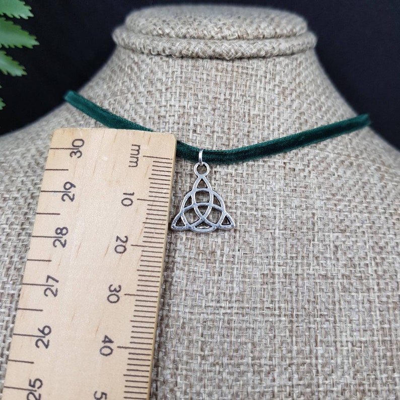 May include: A green velvet choker necklace with a silver Celtic knot pendant. The pendant is about 2 cm in size.