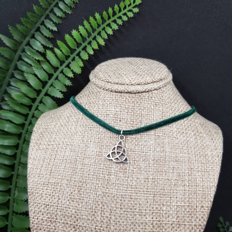 May include: A dark green velvet choker necklace with a silver Celtic knot pendant.