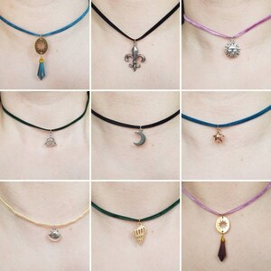 May include: Nine different choker necklaces with various pendant charms. The charms include a sun, a crescent moon, a star, a fleur-de-lis, a crown, a seashell, a Celtic knot, and two sun-shaped pendants with crystals.
