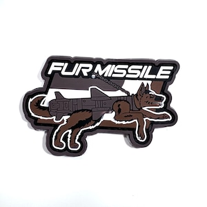 Peut inclure: Graphique marron et noir d'un chien avec un missile attaché à son dos, avec les mots "FUR MISSILE" en lettres blanches. Le chien est couché et le missile est gris.
